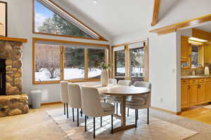 Dining space featuring a wealth of natural light, a fireplace, high vaulted ceiling, and light wood-type flooring