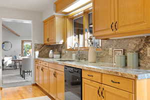 Kitchen featuring tasteful backsplash, sink, light hardwood / wood-style floors, and black dishwasher