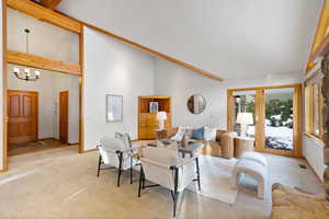 Carpeted living room with beamed ceiling, high vaulted ceiling, and a chandelier