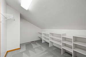 Walk in closet with carpet flooring and vaulted ceiling