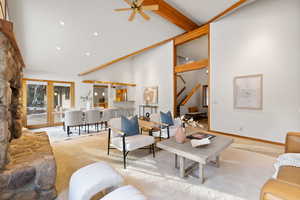 Living room with light carpet, french doors, ceiling fan, a towering ceiling, and beam ceiling