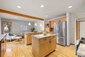 Kitchen with light brown cabinetry, a center island, light hardwood / wood-style flooring, and appliances with stainless steel finishes