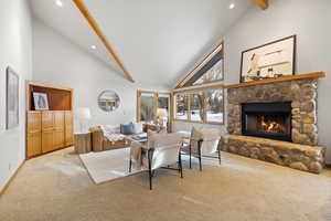 Carpeted living room featuring a fireplace, high vaulted ceiling, and beamed ceiling