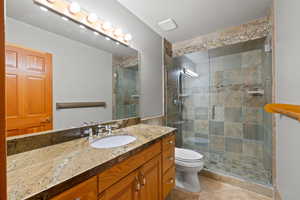 Bathroom with tile patterned floors, vanity, toilet, and a shower with shower door