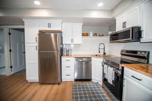 Kitchen with appliances with stainless steel finishes, white cabinetry, and sink