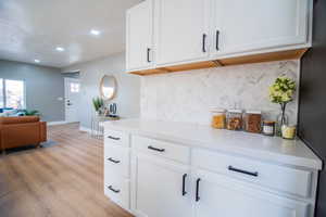 Kitchen featuring tasteful backsplash, stainless steel refrigerator, light hardwood / wood-style flooring, and white cabinets