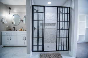 Bathroom featuring a tile shower and vanity