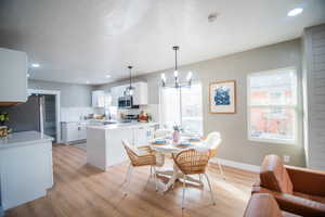 Dining area featuring an inviting chandelier, a textured ceiling, and light hardwood / wood-style flooring