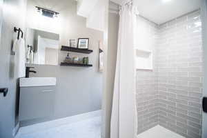 Bathroom with curtained shower and sink