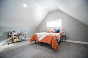 Carpeted bedroom featuring vaulted ceiling