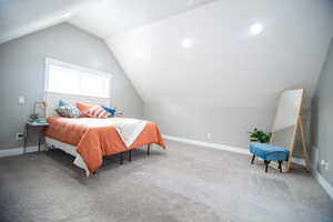 Bedroom featuring carpet floors and vaulted ceiling