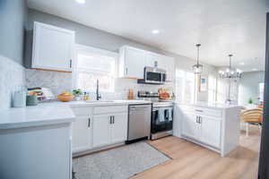 Kitchen with appliances with stainless steel finishes, white cabinetry, and sink