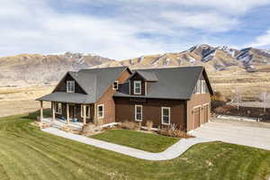 Back of property featuring a mountain view, a porch, a garage, and a yard