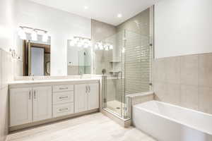 Bathroom with vanity, shower with separate bathtub, and tile walls