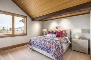 Bedroom featuring lofted ceiling, a mountain view, wood ceiling, and light carpet