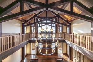 Interior space with beamed ceiling, hardwood / wood-style flooring, high vaulted ceiling, and a notable chandelier