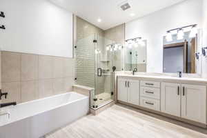 Bathroom featuring hardwood / wood-style flooring, vanity, and shower with separate bathtub