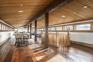 Unfurnished dining area with hardwood / wood-style floors, plenty of natural light, and lofted ceiling with beams