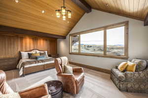 Carpeted bedroom with lofted ceiling with beams and wooden ceiling