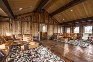 Living room featuring wooden walls, beamed ceiling, wood-type flooring, and wooden ceiling