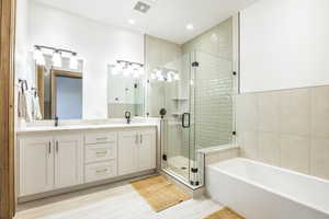 Bathroom featuring vanity, separate shower and tub, and tile walls