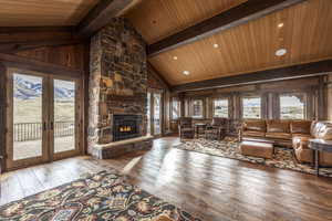 Living room featuring hardwood / wood-style flooring, a stone fireplace, and wood ceiling