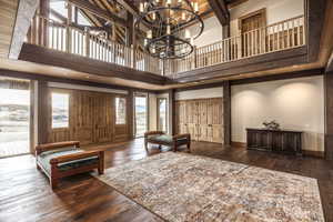 Entrance foyer featuring dark hardwood / wood-style flooring, a towering ceiling, and a notable chandelier