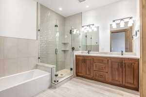 Bathroom with vanity, separate shower and tub, and tile walls