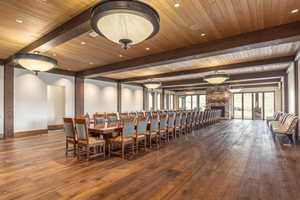 Dining room featuring wood-type flooring, a stone fireplace, beam ceiling, and wood ceiling