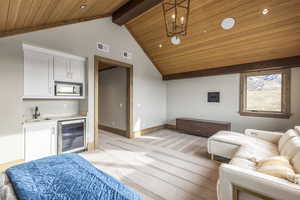 Carpeted living room featuring vaulted ceiling with beams, wine cooler, wet bar, and wooden ceiling