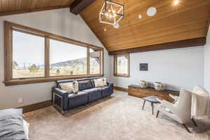 Carpeted living room featuring a mountain view, a chandelier, plenty of natural light, and wood ceiling