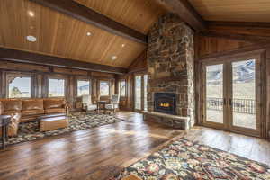 Unfurnished living room with a fireplace, beamed ceiling, hardwood / wood-style flooring, and wooden ceiling