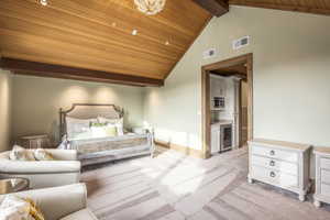 Bedroom with wine cooler, ensuite bathroom, wooden ceiling, and light carpet