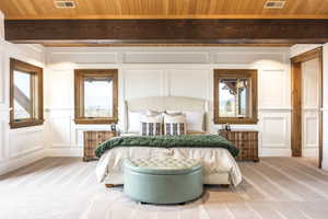 Carpeted bedroom with multiple windows, beamed ceiling, and wood ceiling