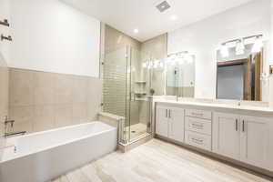 Bathroom with vanity, tile walls, and plus walk in shower