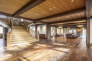 Stairs featuring beam ceiling, hardwood / wood-style floors, wooden ceiling, and plenty of natural light