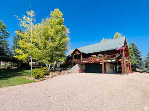 Log-style house with a deck and a front lawn