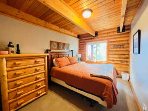 Bedroom featuring light carpet, beam ceiling, rustic walls, and wood ceiling