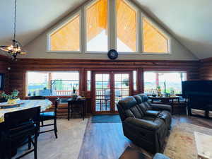 Living room featuring a chandelier, hardwood / wood-style flooring, high vaulted ceiling, and log walls