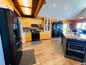 Kitchen with lofted ceiling with beams, light brown cabinetry, sink, and appliances with stainless steel finishes