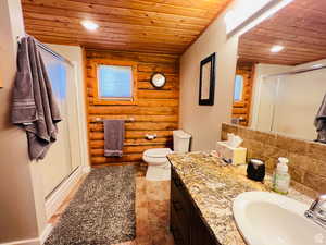 Bathroom featuring backsplash, rustic walls, wood ceiling, a shower with door, and wood-type flooring