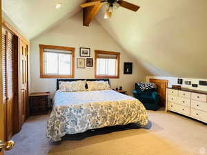 Bedroom with ceiling fan, lofted ceiling with beams, light carpet, and a closet