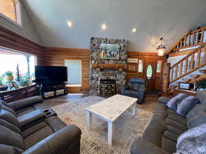 Living room featuring a stone fireplace, wood-type flooring, and high vaulted ceiling