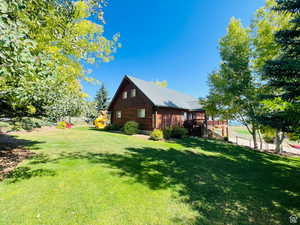 View of property exterior with a yard and a wooden deck