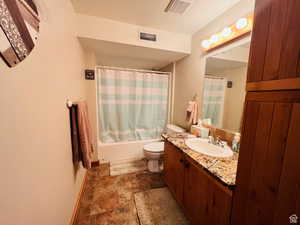 Full bathroom with vanity, shower / bath combination with curtain, and toilet