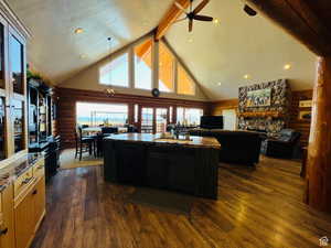 Kitchen with beamed ceiling, dark hardwood / wood-style flooring, high vaulted ceiling, and a kitchen island