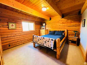 Carpeted bedroom with log walls, beam ceiling, and wooden ceiling