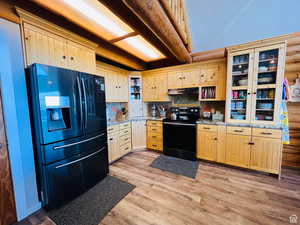 Kitchen featuring light stone countertops, light brown cabinetry, tasteful backsplash, black appliances, and light hardwood / wood-style floors