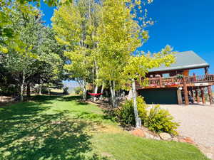 View of front of house with a garage, a front lawn, and a wooden deck