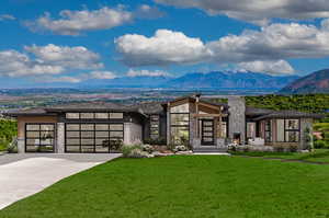 View of front of property featuring a mountain view, a garage, and a front lawn